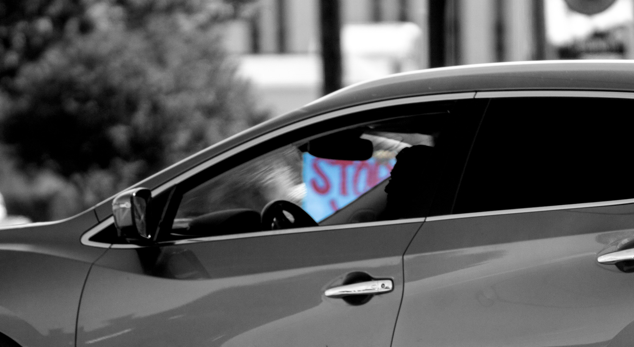 Artistic edit: protest sign reflected in car window
