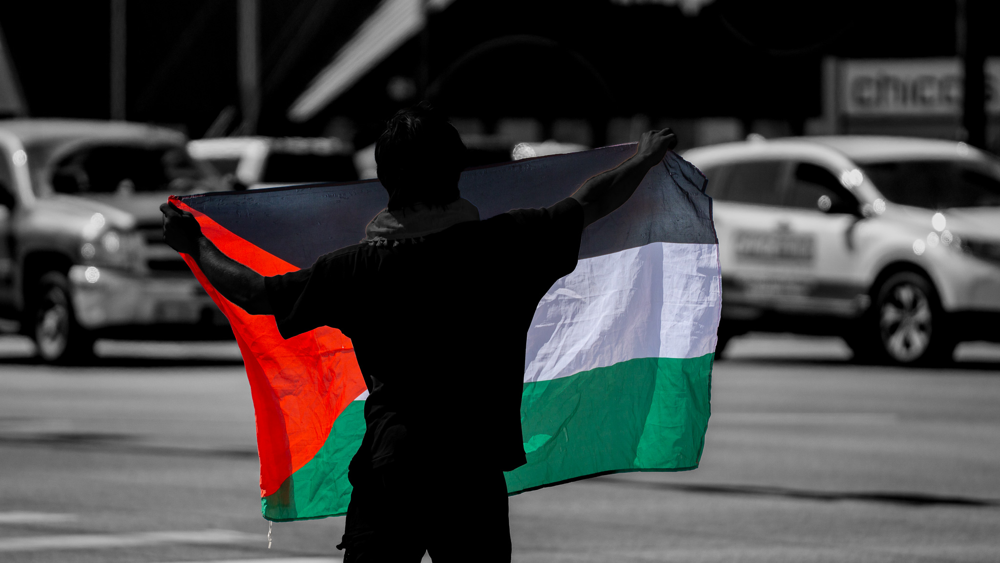 Artistic edit: figure with Palestinian flag in street