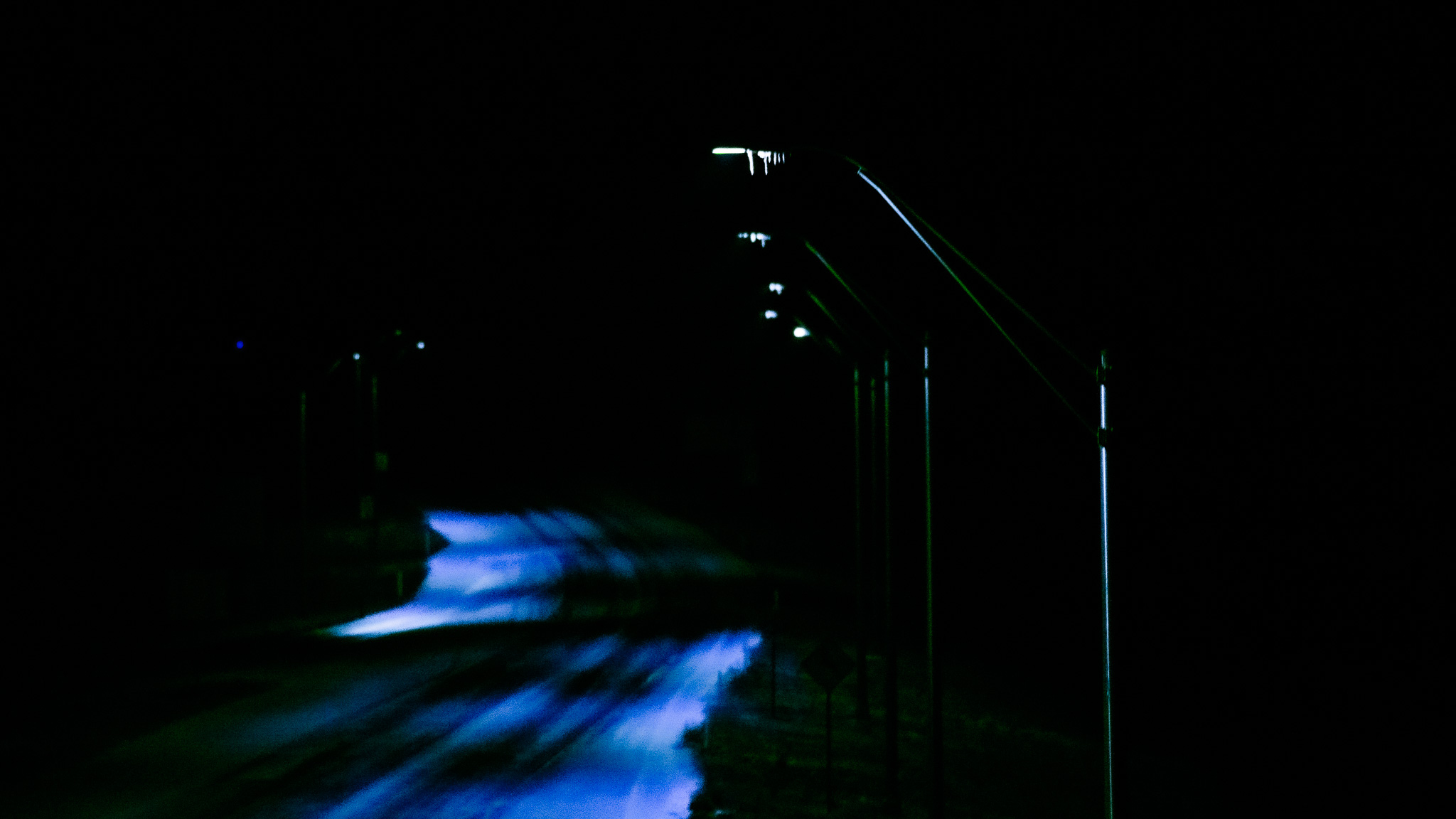 Artistic edit: empty road at night under cool blue light
