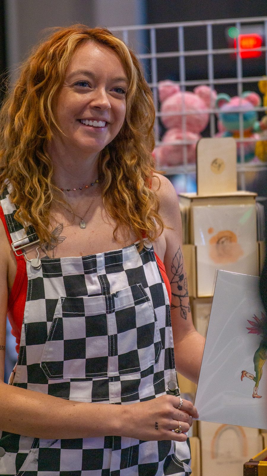 Smiling attendee in checkered overalls at an artist's vendor booth