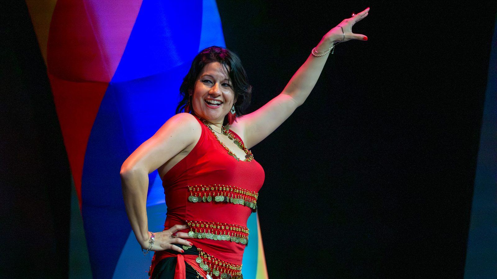 Dancer in a red beaded costume smiling mid-performance