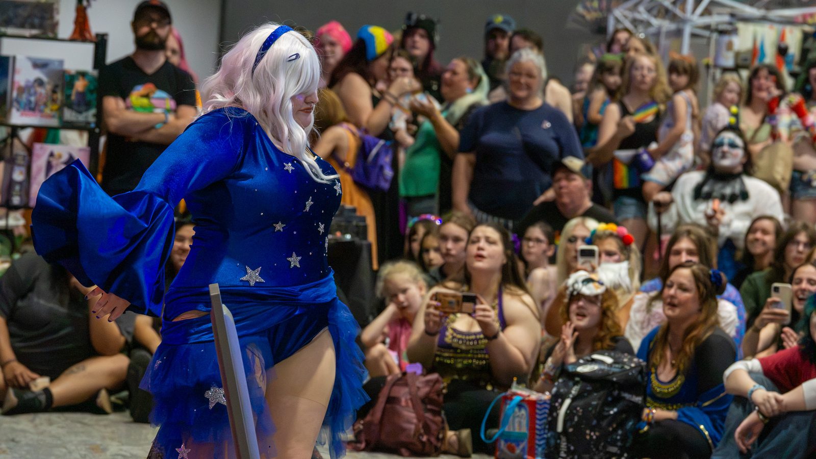 Dancers in blue costumes performing for a packed audience