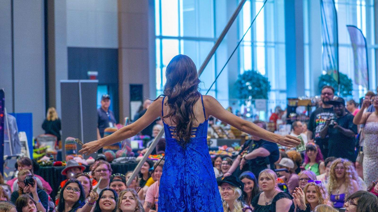 Performer working a full convention-hall crowd from the runway