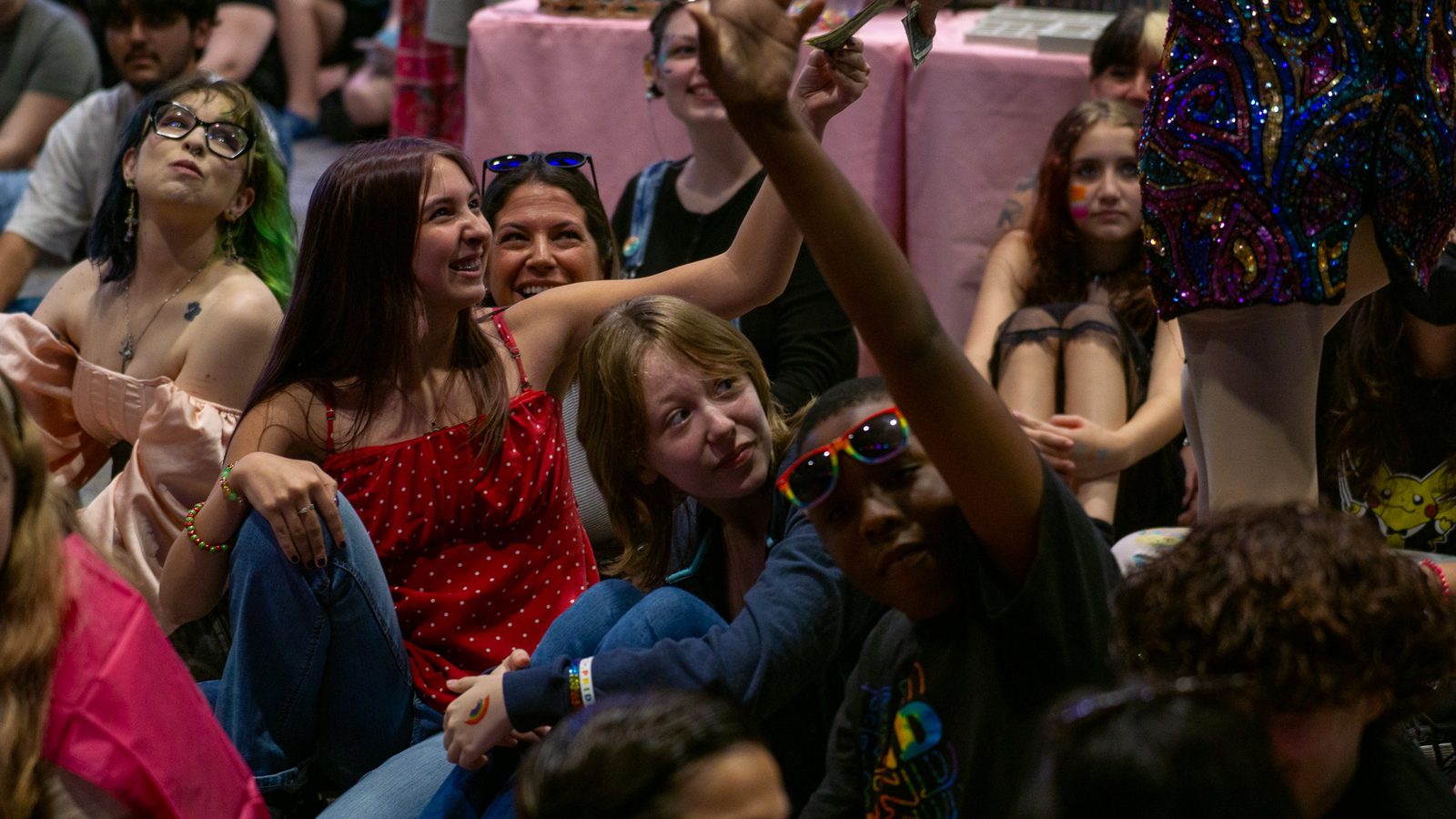 Smiling attendees reaching up to tip a performer during the show