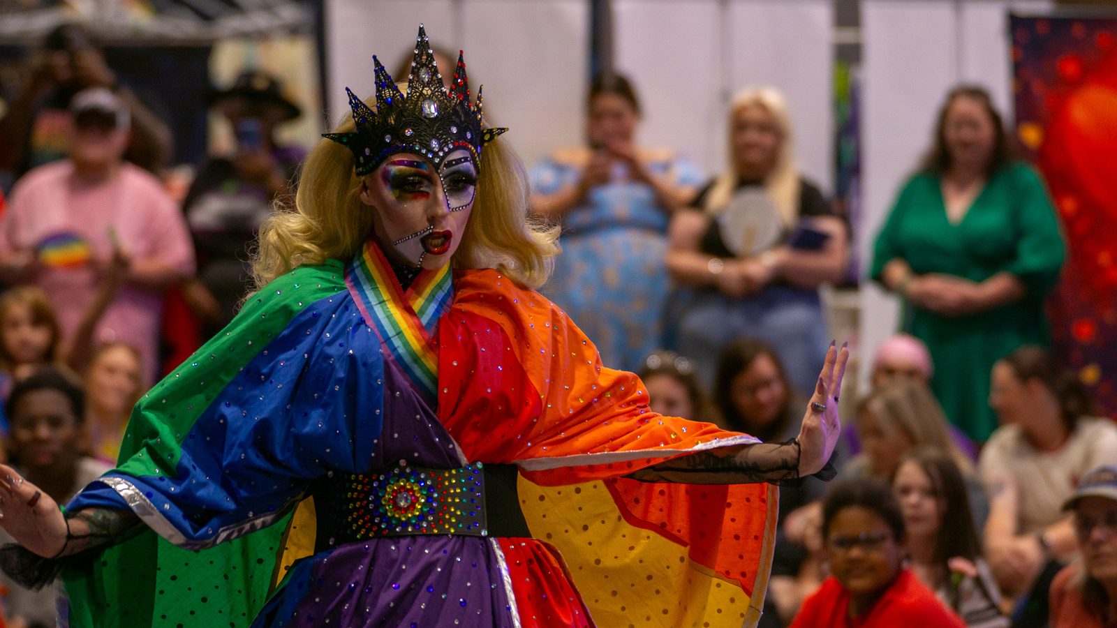 Performer sharing a moment with attendees under a rainbow flag