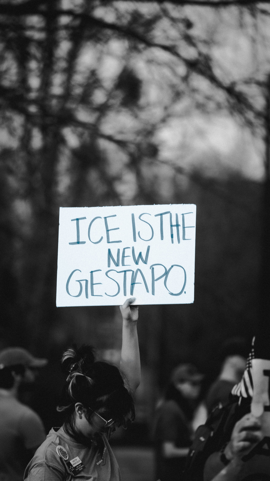 Protester holding ICE is the New Gestapo sign in black and white