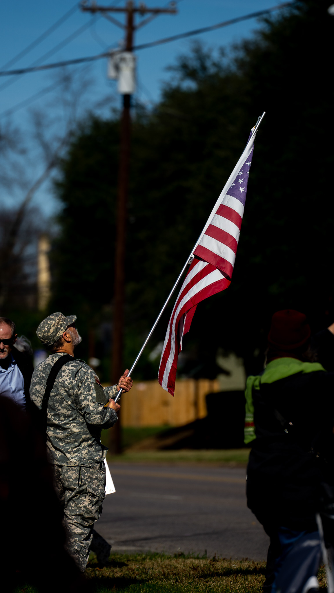 Veteran in fatigues carrying American flag at golden hour